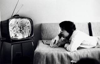 Mike Jagger vendo TV num quarto de hotel de NIorque